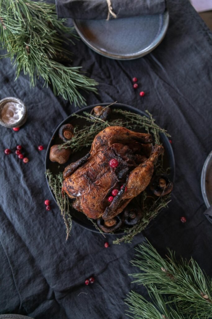 Delicious roasted chicken with herbs and berries on a festive table setting.